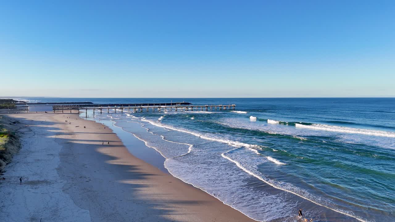 Drone captures serene Gold Coast beach with gentle waves and clear skies, highlighting the natural beauty and tranquility of the shoreline