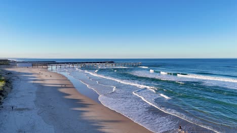 drone captures serene gold coast beach with gentle waves and clear skies, highlighting the natural beauty and tranquility of the shoreline