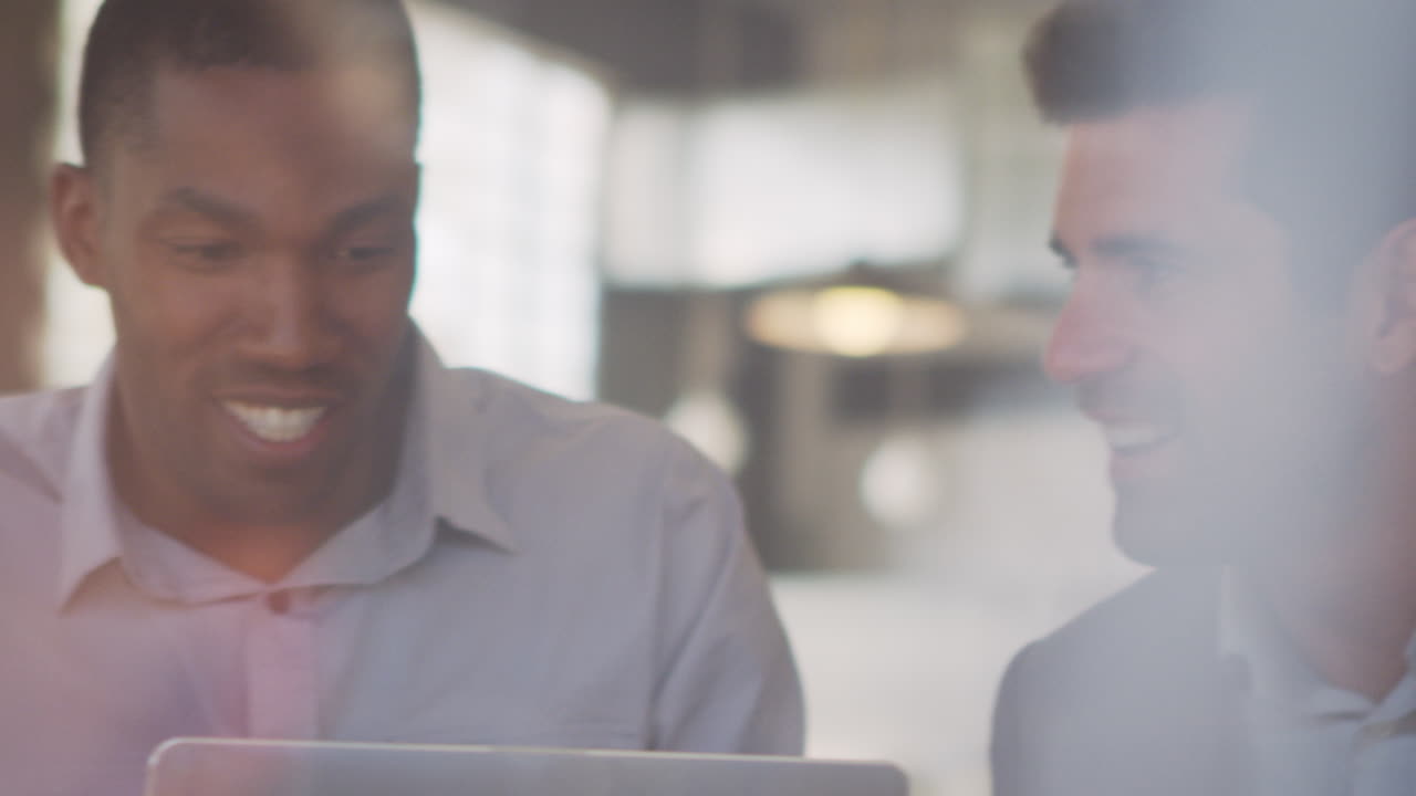Three Businessmen Meeting In Coffee Shop Shot Through Window