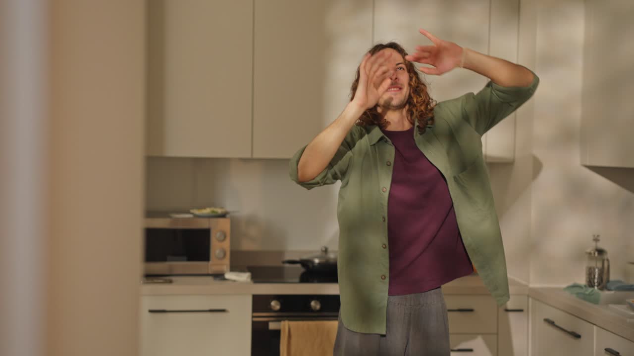 мужчина танцует на кухне.