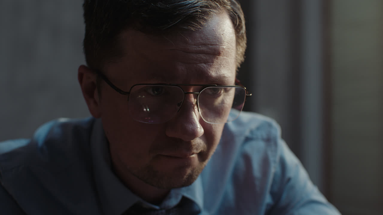 A sad man in a shirt slowly eats breakfast