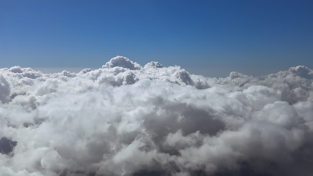 An immersive smooth flight experience over an endless sea of cottony clouds. Aerial footage taken from a jet cockpit at the golden hour