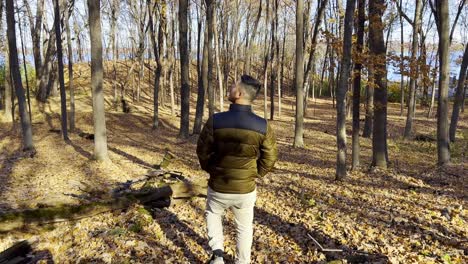 Guy-walking-on-a-forest-during-autumn-with-a-lot-of-yellow-trees-leaves