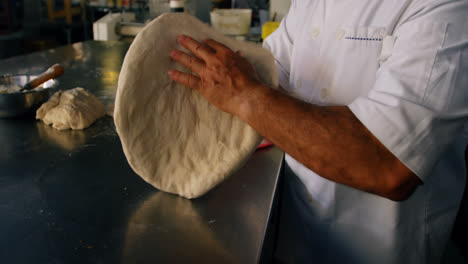 Chef-patting-pizza-dough-with-the-help-of-his-hand-4k