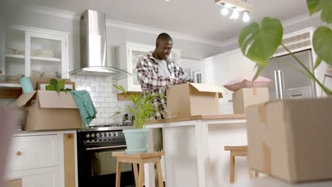 feliz hombre afroamericano desempaquetando cajas en la cocina en casa, cámara lenta