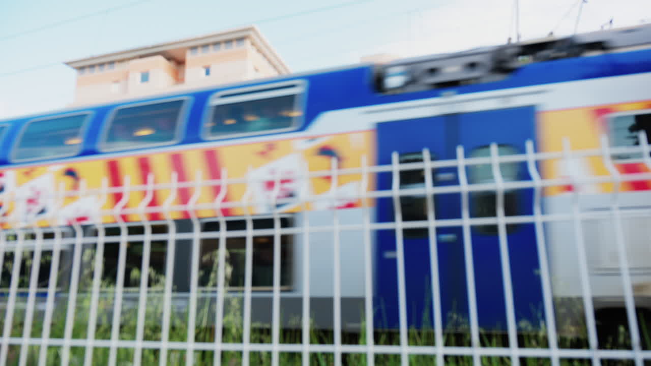 Blurred view of a blue train passing behind a fence through Antibes, France