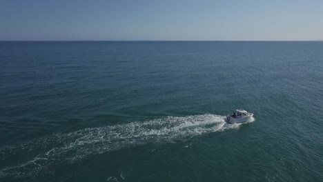 alone white motor boat sailing in open ocean, aerial