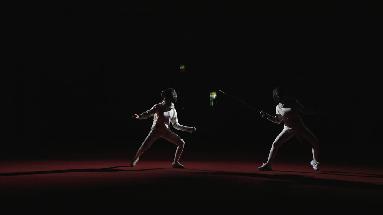 Two men fencing in a dark room