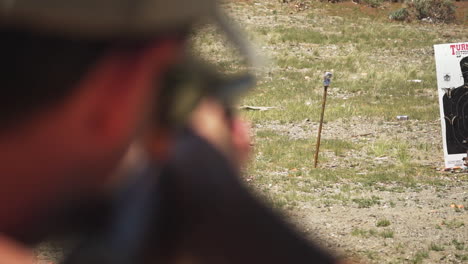 caucasian man strikes target firing a pump-action shotgun at an outdoor shooting range