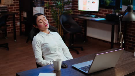 tired employee asleep on computer desk chair suddenly waking up