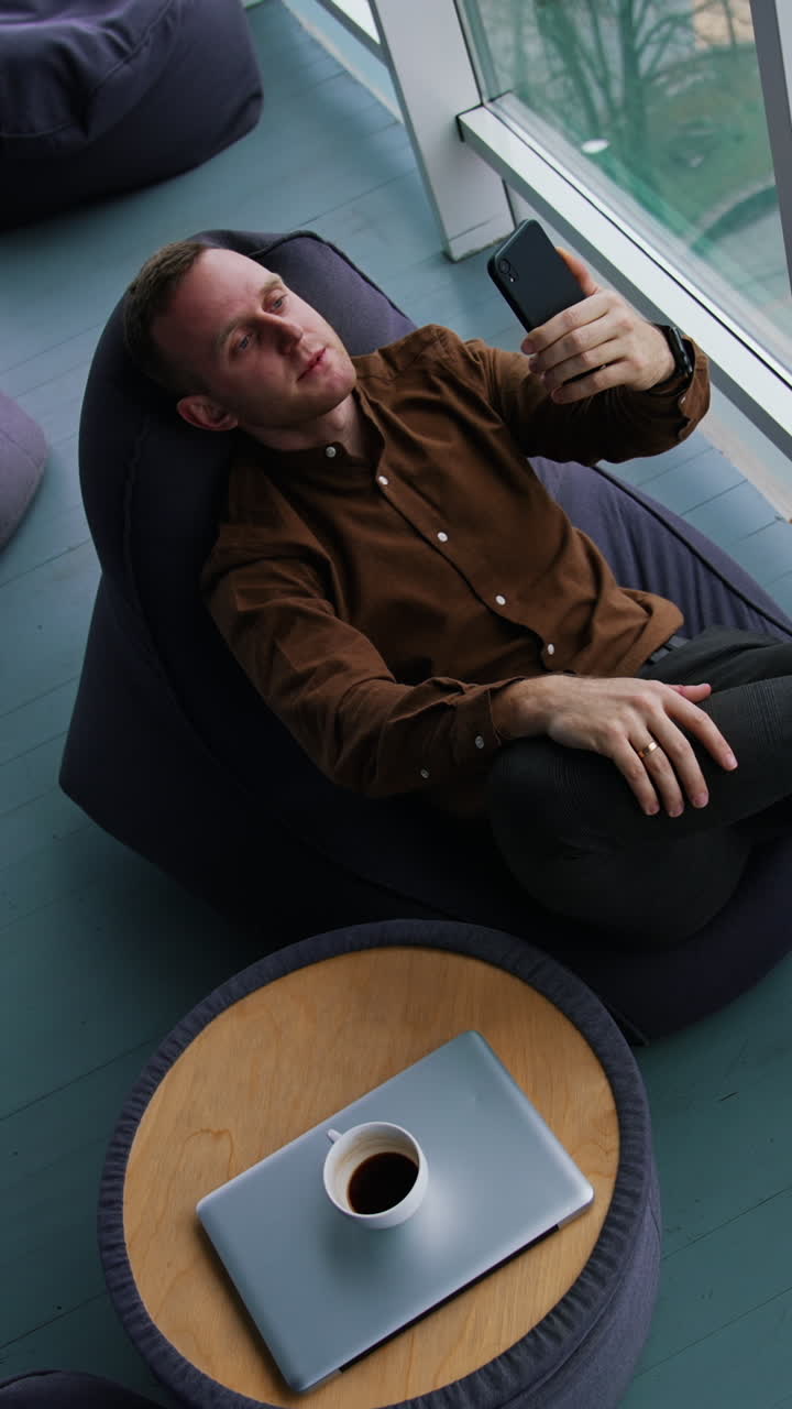 Happy young businessman using smartphone in office Vertical video