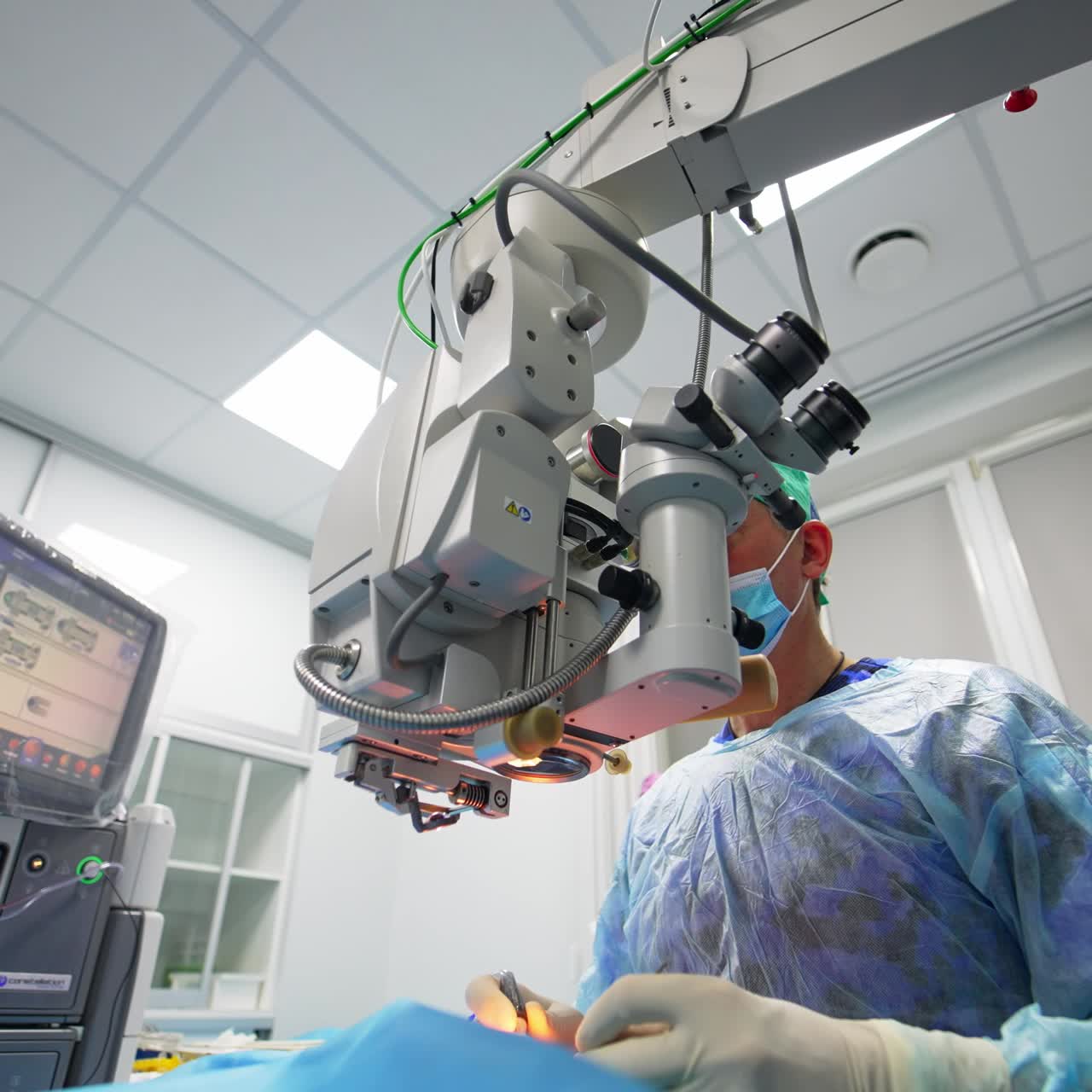 Ophthalmic specialist performing the operation with the help of advanced equipment. Surgeon looking into binoculars of apparatus. Low angle view