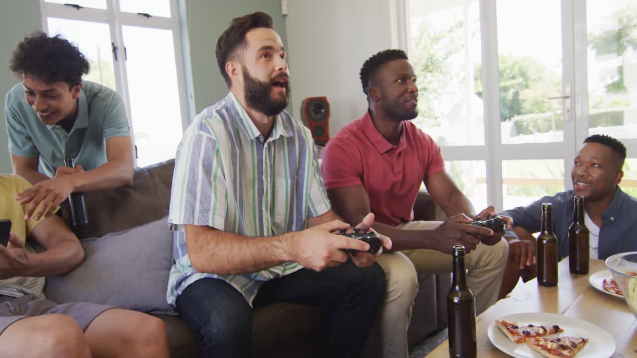Happy diverse male friends watching tv and drinking beer in living room