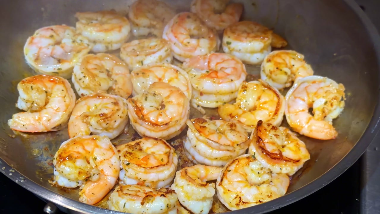 Seasoned shrimp sizzling in a hot skillet with garlic butter and herbs, golden sear and juicy texture—quick homemade seafood cooking closeup.