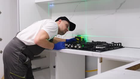 a worker installs a new gas stove and measures with a laser