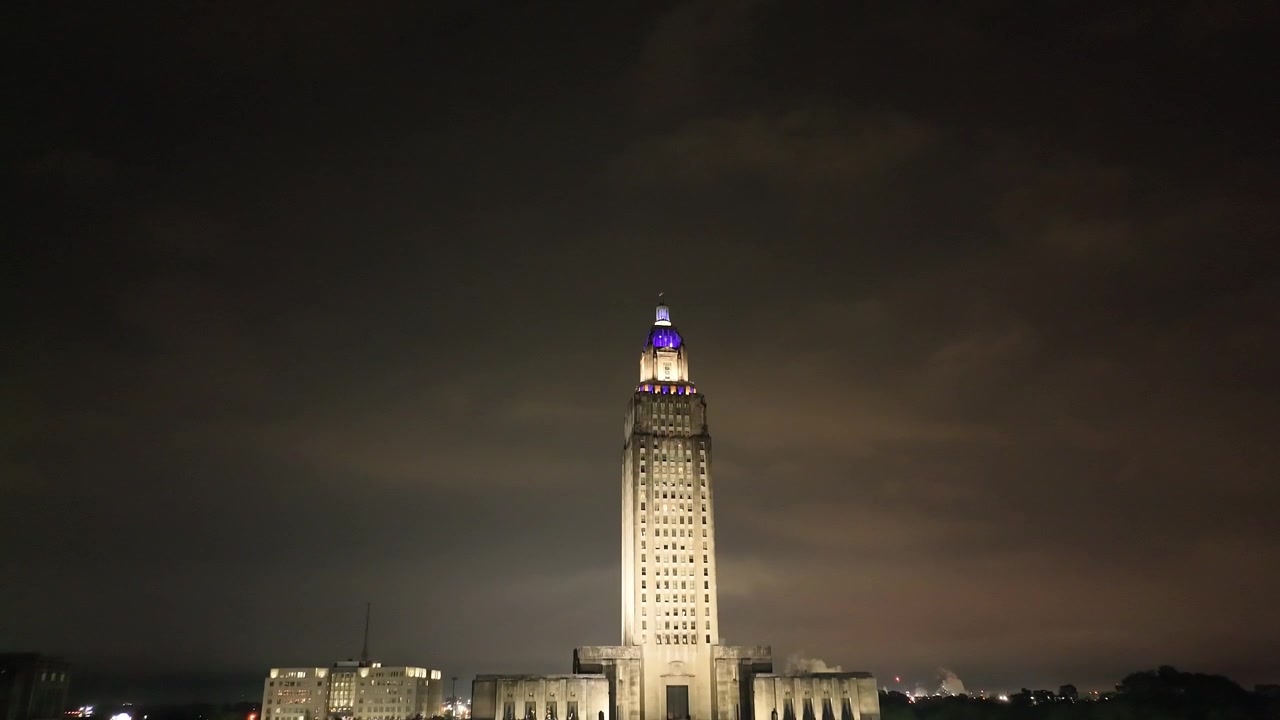 edificio del Campidoglio dello stato della Louisiana a Baton Rouge, Louisiana, di notte, con riprese aeree di un drone che scende verso gli alberi