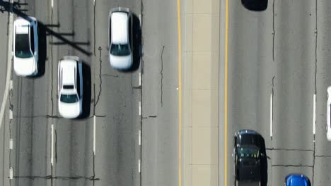 Six-lanes-of-traffic-driving-slowly,-Los-Angeles-LA-expressway,-aerial-drone-birds-eye-top-down-view