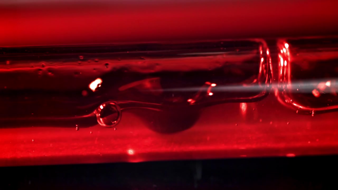 Líquido Vermelho com Bolhas Fluindo por um Tubo de Vidro com Feixe de Luz