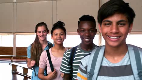 portrait of happy students standing with schoolbags in campus