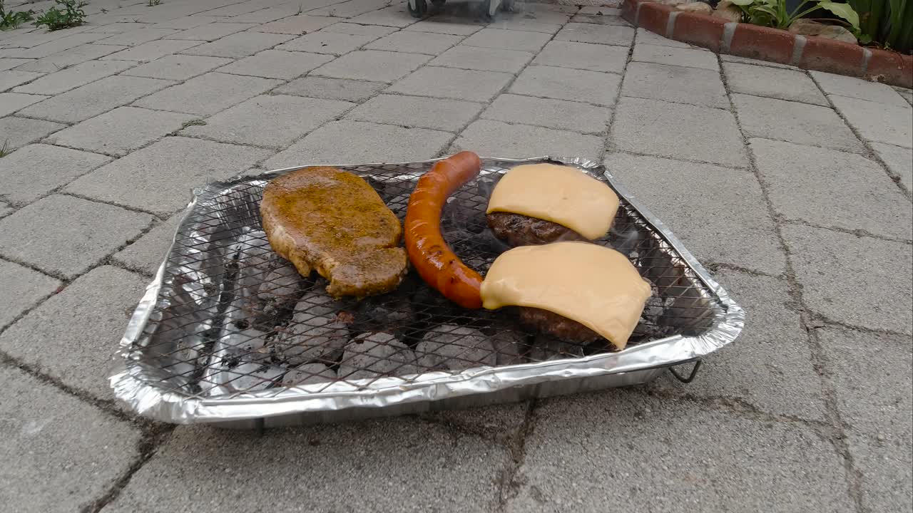 vista bloqueada de la mini parrilla de barbacoa desechable con diferentes y hamburguesas con queso en el suelo de baldosas a cámara lenta