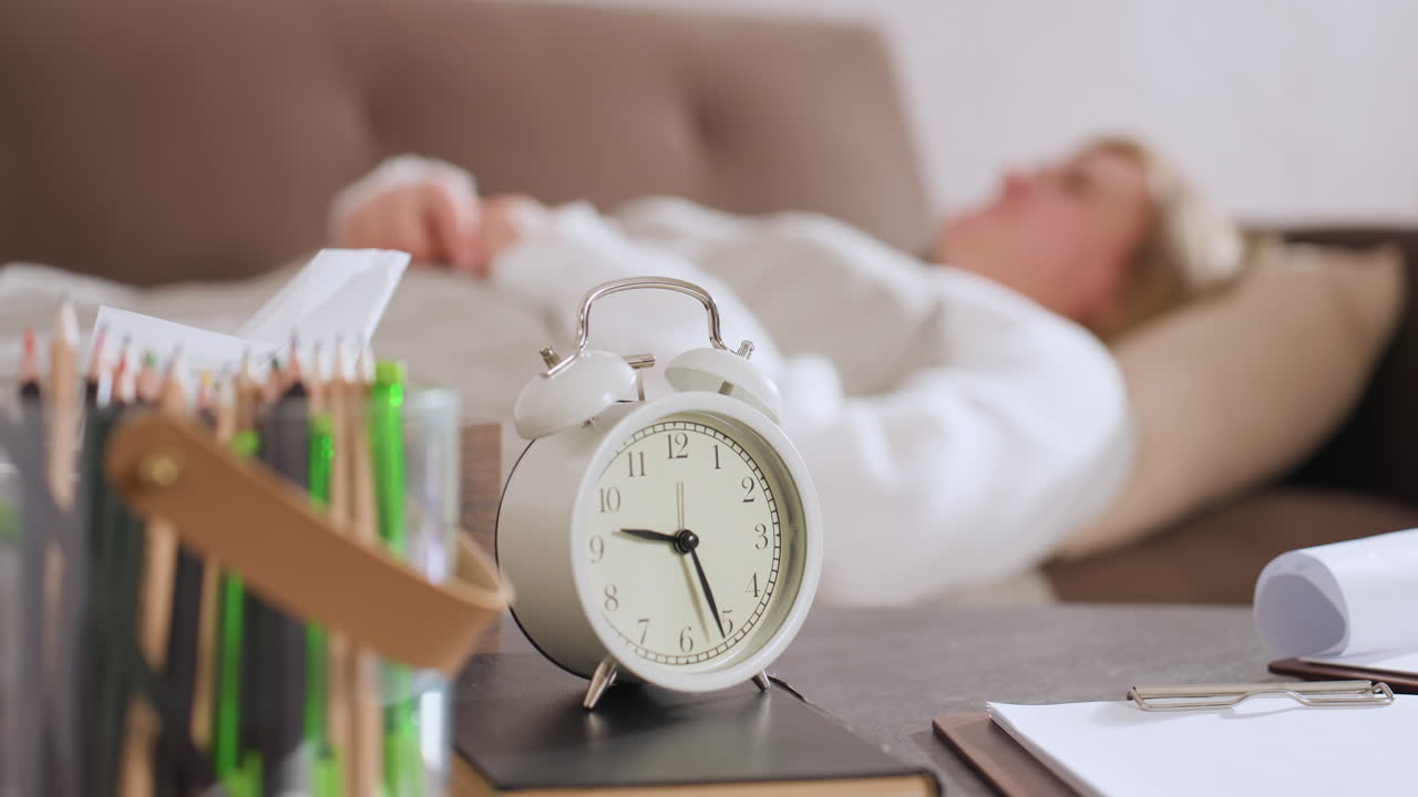 Retro modern clock reading past nine on desk with colored pencils pad note near woman reclining on sofa blurred background setting evoking calm therapeutic consultation environment