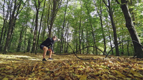 man with battle rope in park. athletic young man with battle rope doing exercise