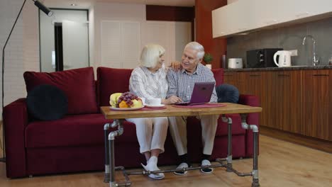 una pareja de abuelos ancianos hablando y usando una computadora portátil digital en casa. compras por internet