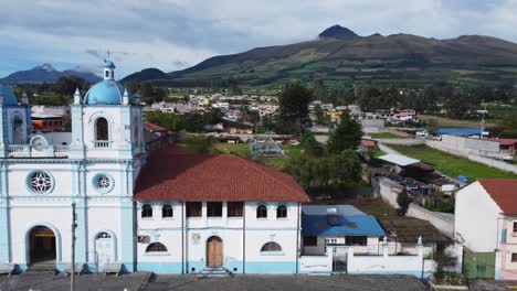 la fachada blanca azul de la iglesia de aloasi con los volcanes illizas y corazon como telón de fondo