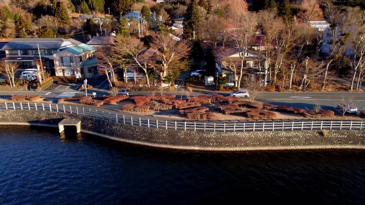 해가 지면 강 의 교외 거리에 황금빛을 비추고, 자동차가 운전하고, 공중에서 볼 수 있습니다.