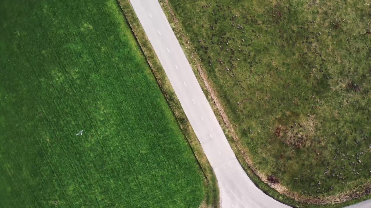 un hombre conduciendo una motocicleta por una pequeña carretera entre campos de hierba