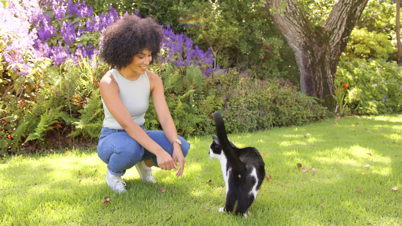 Playing with black and white cat, woman enjoying time in garden outdoors