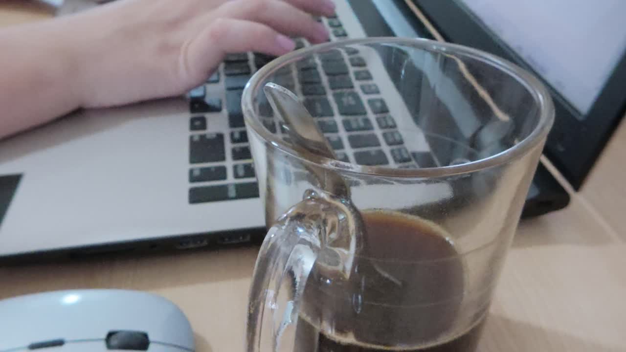 Person drinking coffee and working on laptop