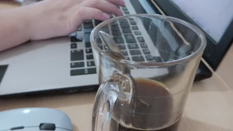 person drinking coffee and working on laptop