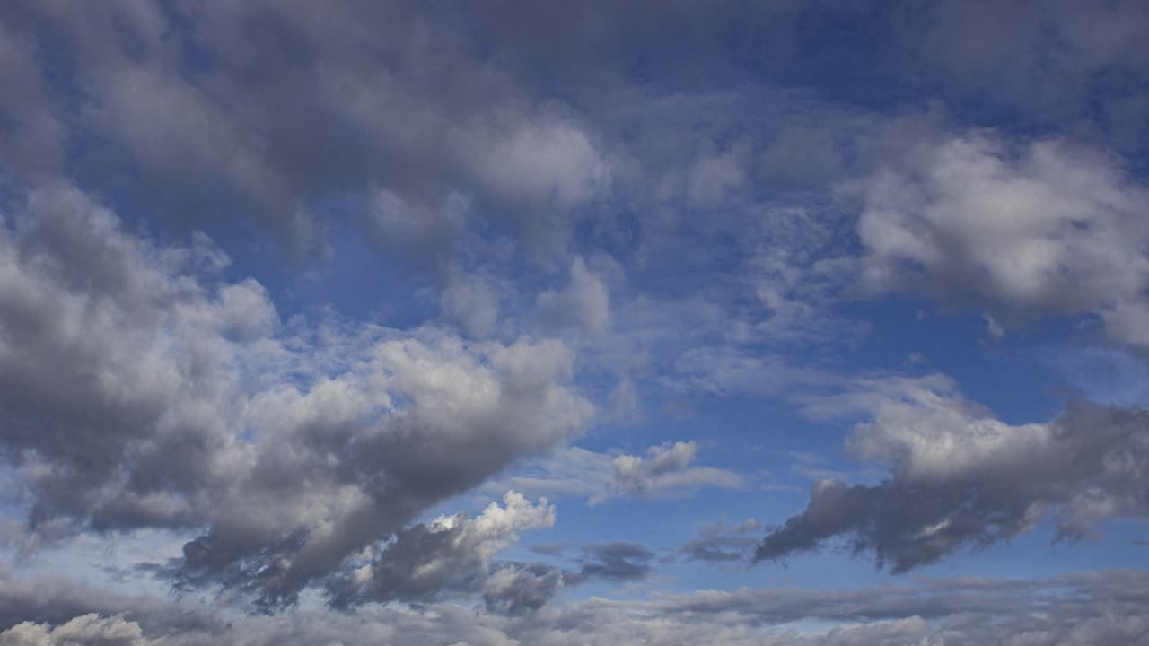 vista de lapso de tiempo de nubes grises hinchadas que avanzan lentamente bajo el cielo azul