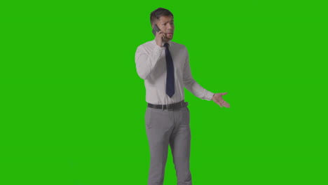 Studio-Shot-Of-Angry-Businessman-In-Suit-Talking-On-Mobile-Phone-Against-Green-Screen-