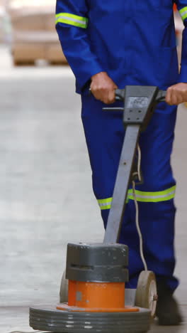 male warehouse worker cleaning warehouse floor