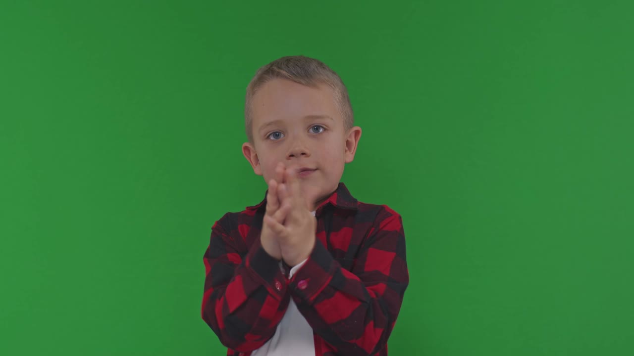 Portrait of a boy having fun and clapping his hands on a green screen