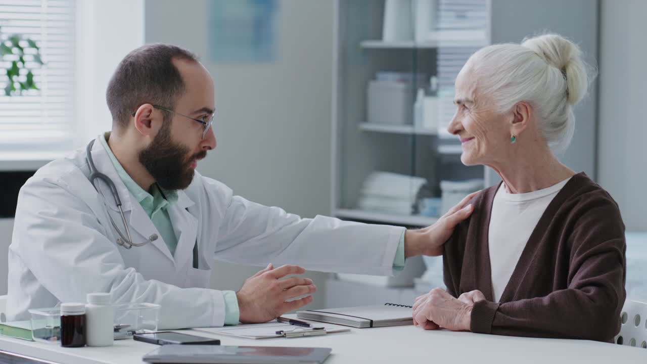 Doctor Comforting Elderly Patient during Consultation in Clinic