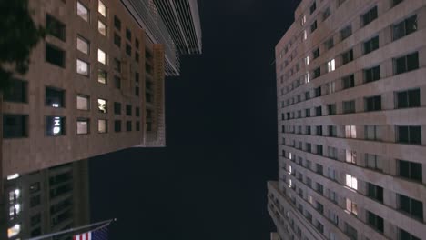 la: downtown la skyscrapers looking up from the sunroof of a car at night with lens flare and american flag - los angeles california, usa