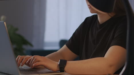 freelancer-woman-is-working-from-home-at-evening-typing-text-on-laptop-details-view-on-hands-pan-to-face-busy-female-worker-overtime-work