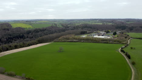 toma aérea de sobrevuelo de campo y árbol con industria visible en yorkshire, inglaterra durante un día nublado de primavera
