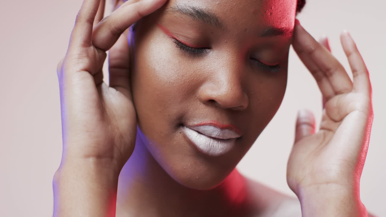 Femme afro-américaine aux cheveux courts foncés sous une lumière bleue et rose, au ralenti