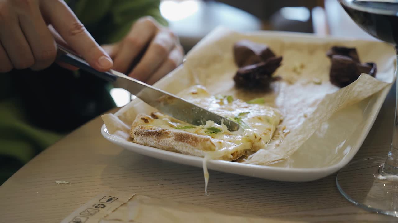 칼이 접시 위에 있는 피자를 자르고, 한 남자가 카페에서 피자를 먹고, 아주 가까운 장면을 찍는다.
