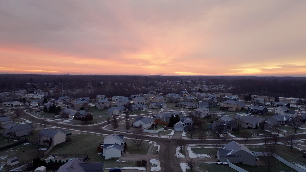 4K drone-luftoptagelser af en livlig vintersolopgang over forstadskvarterer i Grand Rapids, Michigan, med sneklædte hustage, farverig himmel og rolig morgenstemning
