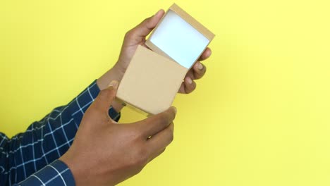 a man's hands opening a small brown gift box