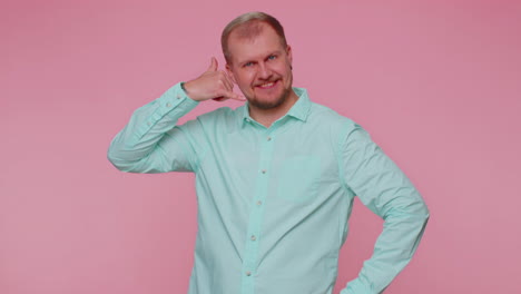 Joyful-one-man-in-blue-shirt-looking-at-camera-doing-phone-gesture-like-says-hey-you-call-me-back