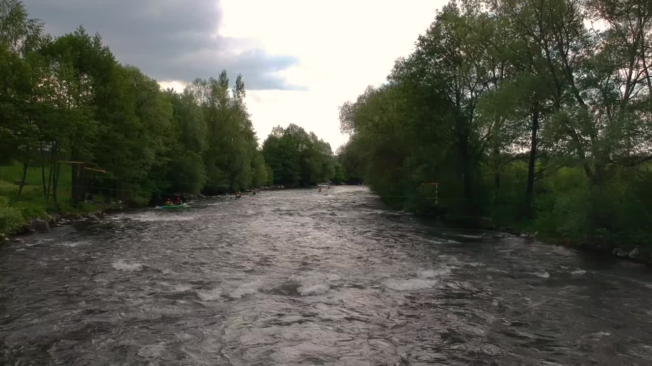 Luftfoto fra drone, der flyver lavt over en hurtigtstrømmende flod med kajakroere