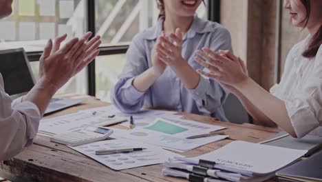 young asians clap each other for a successful project. in smart casual wear and smiling while working in a creative office