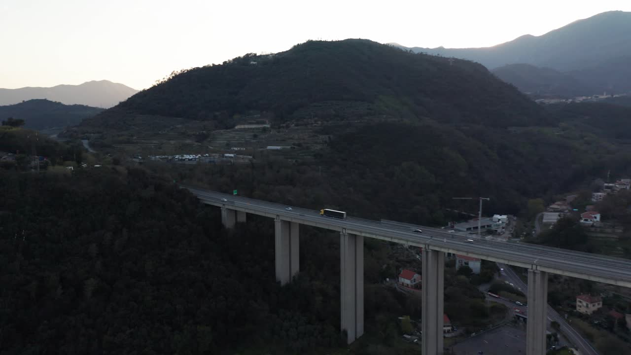 트럭 과 자동차 가 산 들 사이 에 있는 높은 다리 를 가로질러 운전 하는 항공기