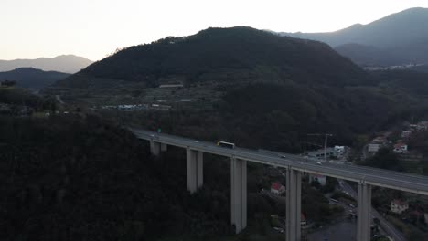 Aerial-of-truck-and-cars-driving-over-high-viaduct-overpass-between-mountains